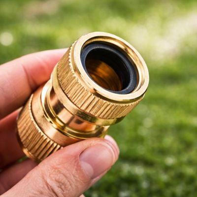 Raccord tuyau arrosage femelle femelle QuickBrass  entre les doigts d'un jardinier