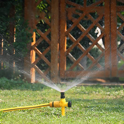 Arrosage automatique Aqua360 en action devant une porte de jardin en bois