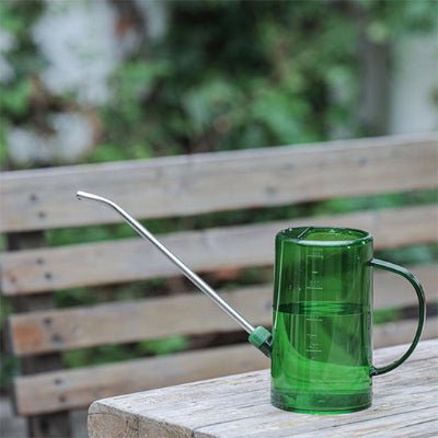 Arrosoir translucide 1L Vintage Garden  vert sur un terrasse de jardin extérieur