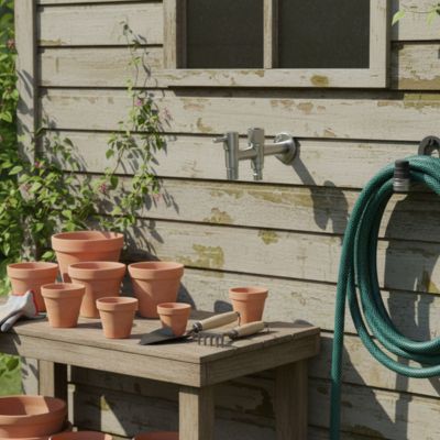 Robinet double sortie FrosProtect sur maison bois près table rempotage