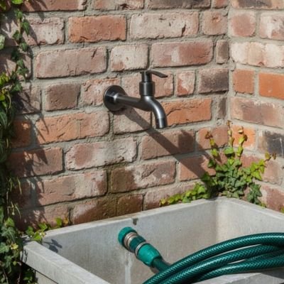 Robinet pour exterieur Arrosage Optimal+ au dessus d'un lavabo au mur maison brique